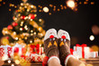 Detail of woman legs with knitted socks, Christmas tree with gifts on background