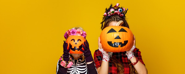 Wall Mural - mother and child holding jack-o-lantern pumpkins in front of faces