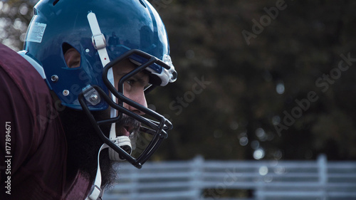 Plakat Boczny widok zakończenie głowa zdecydowany futbol amerykański gracz jest ubranym ochronnego błękitnego hełm podczas dopasowania