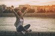 © inesbazdar - Happy woman enjoys sitting at the riverbank with her arms outstretched.