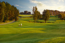 Man With His Son Golfers Walking On Perfect Golf Course At Summer Evening