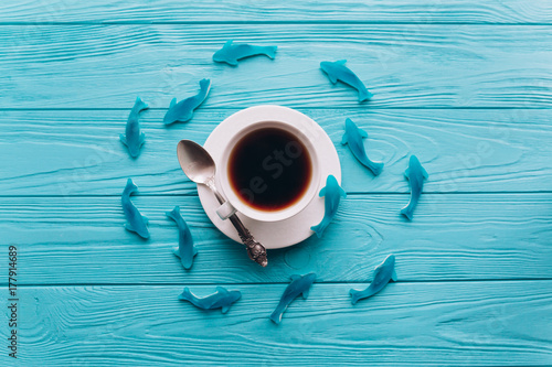 Plakat Filiżanka kawy na drewnianym błękitnym tle z ryba.