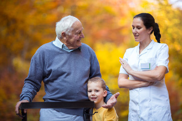 Wall Mural - Young grandson spending time in the park with disabled senior grandfather