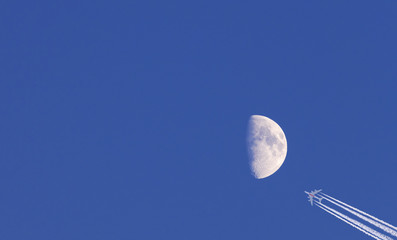 moon and commercial airplane on blue sky background