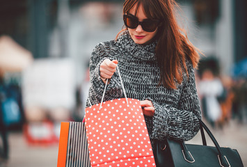 Pretty woman at the city street looking into shopping bag