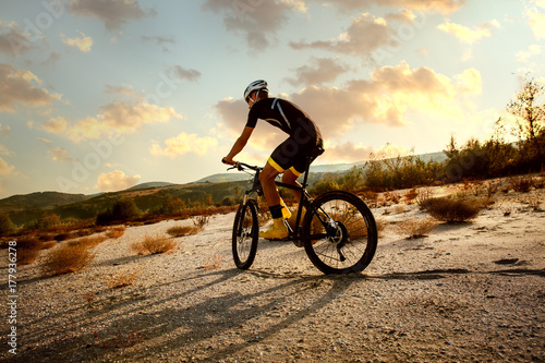 Zdjęcie XXL Młody człowiek jedzie rower górskiego nad pustynią. Zmierzch.