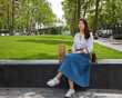 © papa - Beautiful young woman with shopping sitting in the city Park and drink coffee.