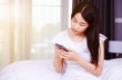 © geargodz - happy woman using a phone in her hand on bed in bedroom