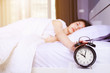 © geargodz - woman sleeping on bed and rise hand to turn off alarm clock in bedroom