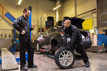 Poster - auto mechanics changing car tires at workshop