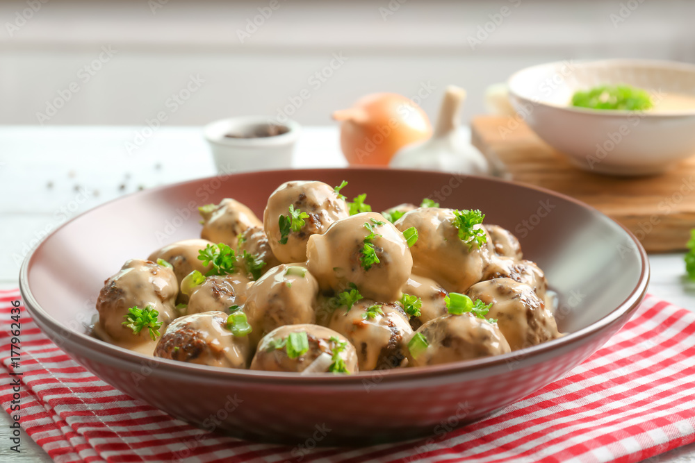 Bowl with delicious meatballs in sauce on table