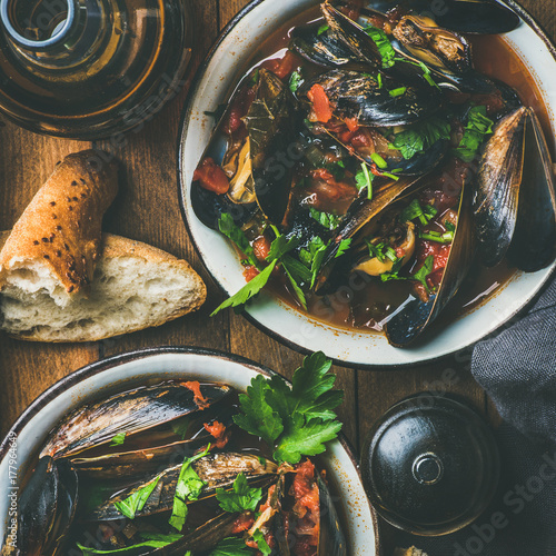 Fotografía Belgian boiled mussels in tomato sauce with fresh parsley in serving metal bowls