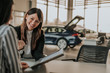 © bnenin - Smiling woman showing car folder in car salon.