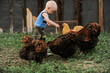 © galitsin - Caucasian boy feeding chickens on a farm.