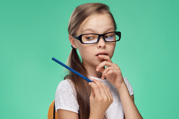 Wall Mural - a schoolgirl in glasses holds a pen on a green background