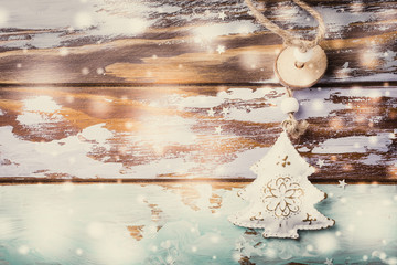 Metal white christmas tree with ornament on old wooden grunge background with snow and copy space. Top view, retro style toned.