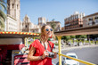 Young happy woman tourist in red dress having excursion in the open touristic bus in Valencia city, Spain