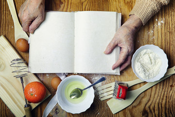 Wall Mural - Open recipe book in the hands of an elderly woman