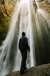 © victortorres/Stocksy - Hiker Looking Up at the top of Glufrafoss Hidden Waterfall