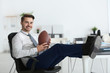 © Africa Studio - Young handsome man with ball for American football in office