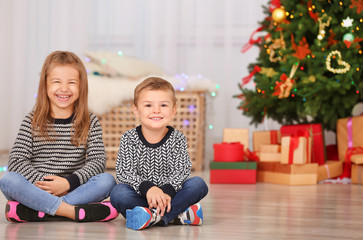 Wall Mural - Cute little children sitting on floor in room decorated for Christmas