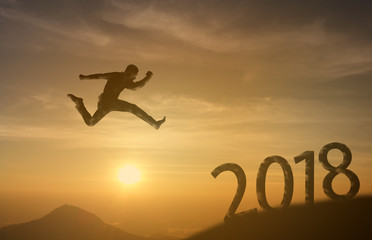2018 brave man successful concept,silhouette man jumping over the sun between gap of the mountain to 2018 new year, feel like a winner, success, finish,reach a goal of live, jobs,work in year coming