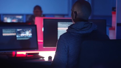  Computer hacker working in a dark room surrounded by computer screens