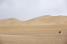 Man Motorcycling Through Desert Sand Dunes
