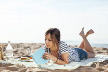 Beautiful Young Woman Reading A Book On The Beach.