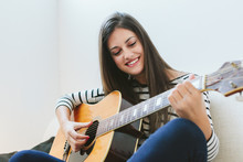 Woman Playing Guitar At Home