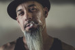 © Rachel Bellinsky/Stocksy - Rugged man with tattoos smokes and gesticulates