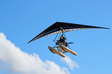 Motorized Hang Glider Flying In The Blue  Cloudy Sky