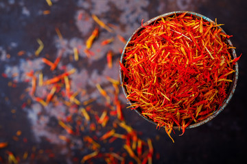 Wall Mural - Dried saffron spice a glass of metal Oriental flavor. Raw Organic pistil powder saffron Red Exotic Seasoning  on black background Dull pestle of orchid flower.