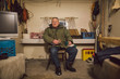 © Ania Boniecka/Stocksy - A grumpy old man sitting inside his trailer