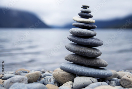 Cuadros en Lienzo Zen balancing pebbles next to a misty lake.