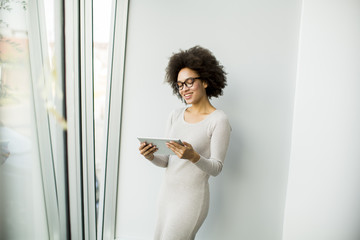 Young African American businesswoman standing wirth tablet in the office by window