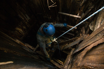 Miner on rope exploring the old mine shaft