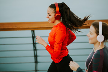 Two young women running by the river