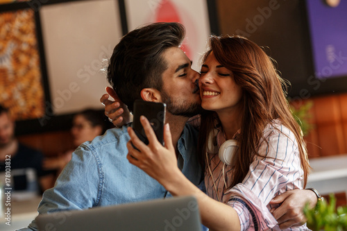 Plakat Młoda para siedzi w kawiarni i relaks na przerwie kawy. Całowanie i co selfie.