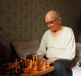 caucasian grand father in eyeglasses thinking chess strategy