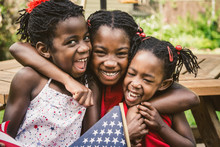 Three African-American Girls In Red, White And Blue USA Flag Outfits Laughing