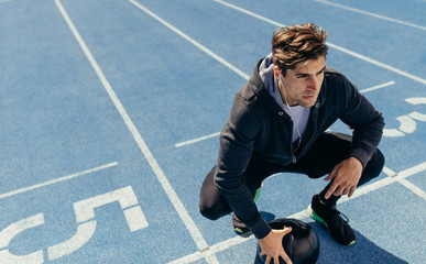 Wall Mural - athlete sitting on the running track with a medicine ball