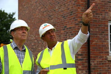 Two men on building site in hard hats and high visibility jackets