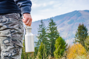 Man holding a bottle on the carpathian mountains background