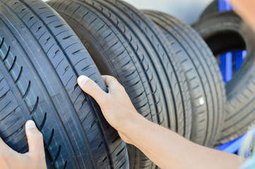 Close up of person checking examining car tyre on the shelf abstract transportation background. Automobile warehouse business, factory production. Protector surface texture