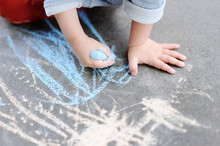 Closeup Photo Of Little Kid Boy Drawing With Colored Chalk On Asphalt