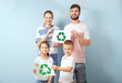 © Africa Studio - Family holding paper sheets with recycling symbol on color background