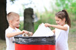 © Africa Studio - Little kids throwing garbage into litter bin outdoors
