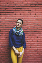 Beautiful Woman Standing In Front Red Brick Wall. Looking At Camera.