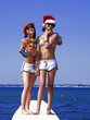© kravik93 - Portrait beautiful women, has haired long hair, blue and white bikini, sunglasses, slim body, happy smile face, red Christmas hat. Tropical hot sea. Having fun together.